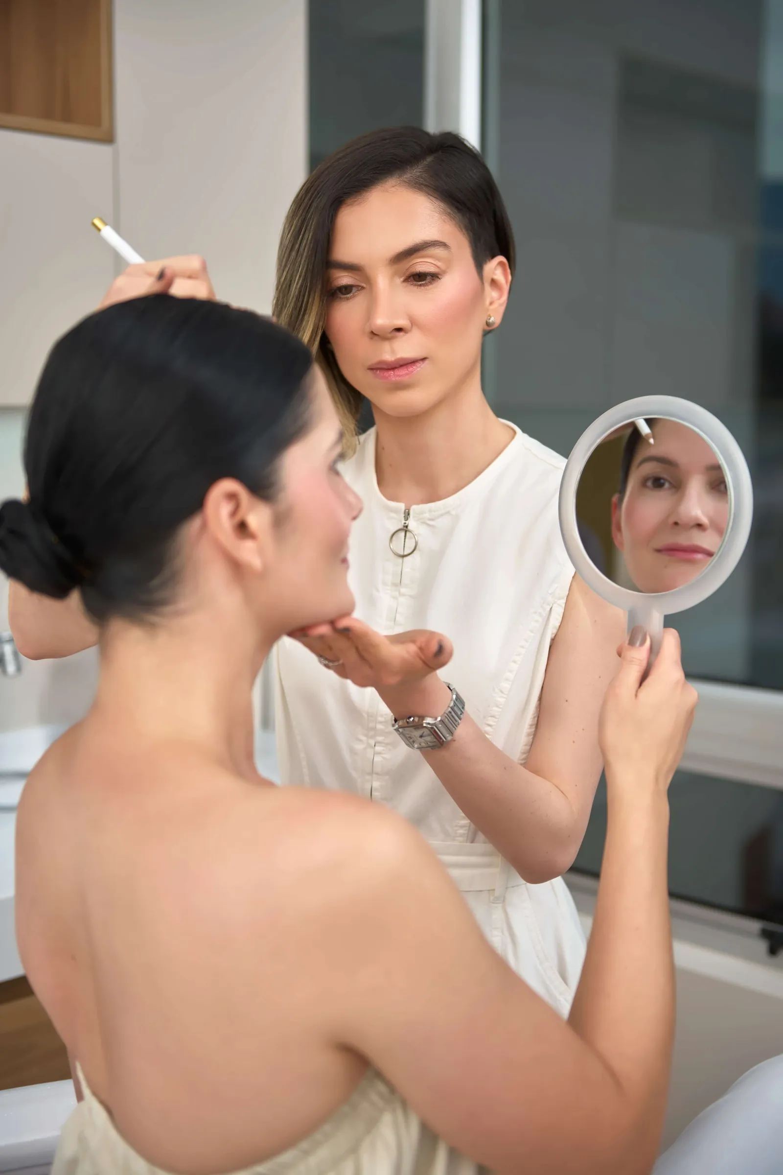 Especialista de Clínica Ohmio realizando valoración facial con espejo de mano a paciente